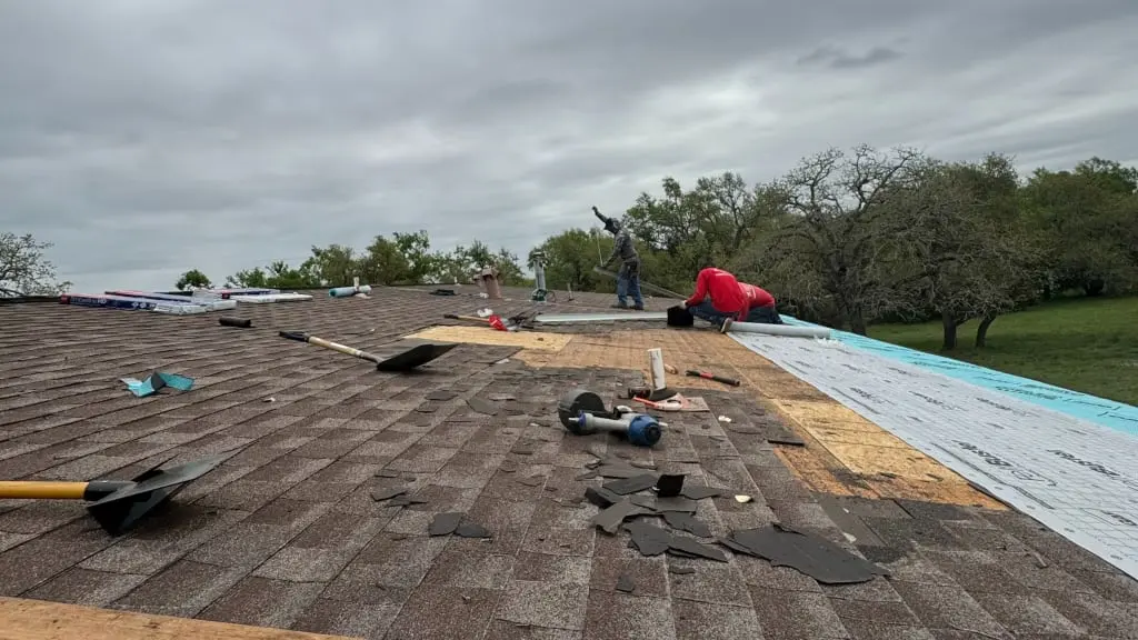 Roofer repairing damaged asphalt shingles on a Central Texas home